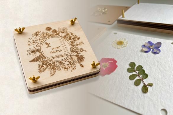 PLANT AMERICA wooden flower press beside an open press with flowers and leaves.
